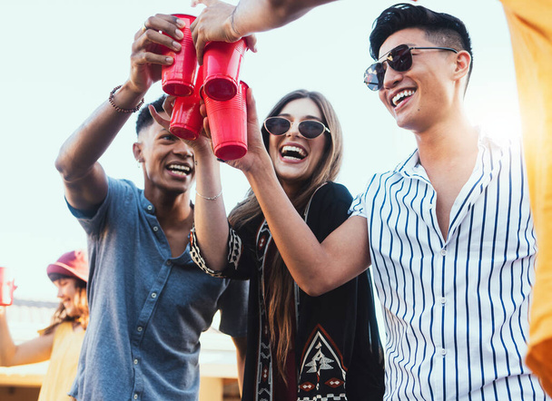 Party, drinks and cheers with friends outdoor to celebrate at festival, happy hour or summer social event. Diversity young men and women people together for toast, happiness and drinking alcohol. - Photo, image