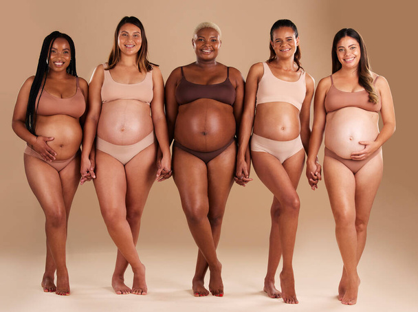 Pregnant, women or diversity portrait with stomach on studio background in body love, baby or community support. Smile, happy or pregnancy friends in underwear for tummy growth or mothers empowerment. - Foto, afbeelding
