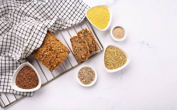 Gluten Free Homemade Bread. Healthy eating, dieting, balanced food concept. Cereals gluten-free (millet, buckwheat), psyllium husks, flax seeds, sunflower seeds on gray marble background.  - Zdjęcie, obraz