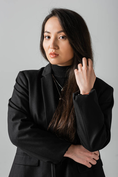 portrait of young asian businesswoman in black suit standing and looking at camera isolated on grey  - Photo, Image