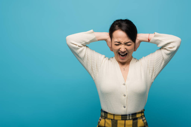 Angry asian woman screaming isolated on blue  - Photo, image