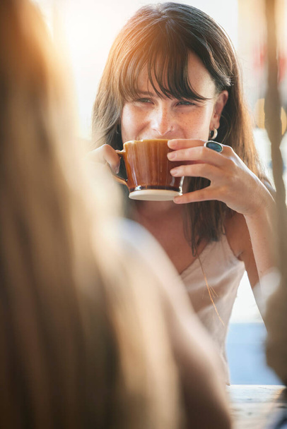 Woman, friends and drinking coffee for conversation, chatting about social life or gossip at an outdoor cafe. Happy female smiling and enjoying a warm beverage, discussion or listening to best friend. - Foto, imagen