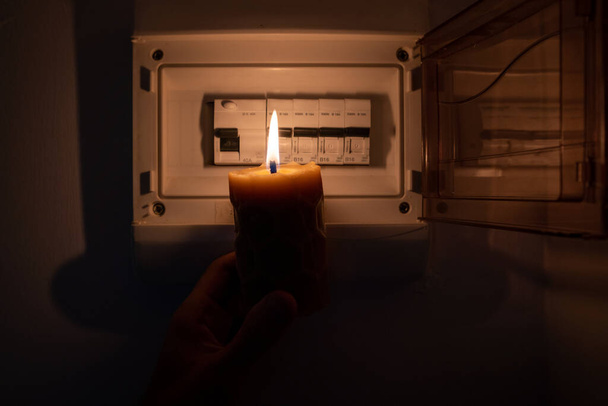 Blackout, electricity switch, lack of energy, power cut - no electricity, the flame of a candle, circuit breaker, electrical outlet plug - Foto, imagen