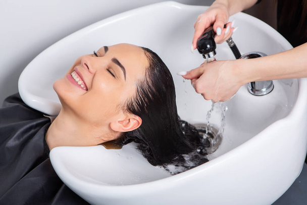 美容室で若い女性のプロの美容師の洗髪髪。美容室で女性の髪の毛を閉じて、ヘアスタイルのコンセプト - 写真・画像