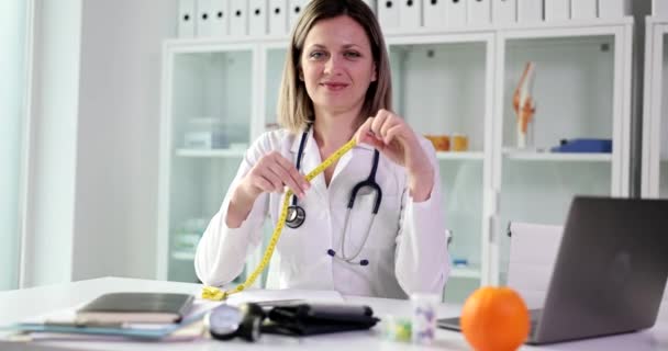 Doctor nutritionist holding centimeter tape in his hands to measure patient waist in clinic 4k movie slow motion. Human body mass index concept - Séquence, vidéo