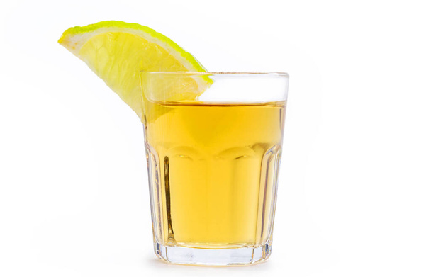 glass of alcoholic drink with lemon, distilled from sugar cane, called in Brazil "pinga" or "cachaca", on isolated white background, Brazillian tipical drink. - Photo, Image