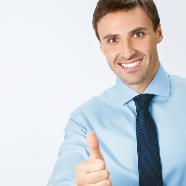Businessman with thumbs up gesture, on grey - Фото, изображение