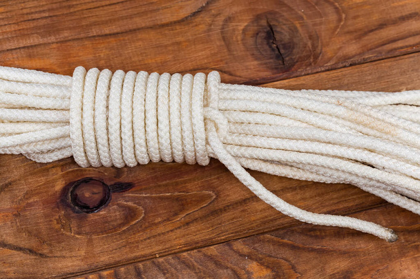 Rope alpine coil knot intended to binding of the climbing rope bight during her storing and transport, top view on an old wooden table - Photo, image