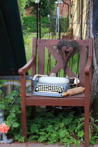 Old wooden chair with typewriter, metal heart and rolling pin - Zdjęcie, obraz