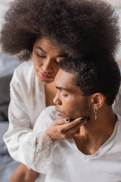 curly african american woman with closed eyes touching face of young boyfriend  - Foto, immagini