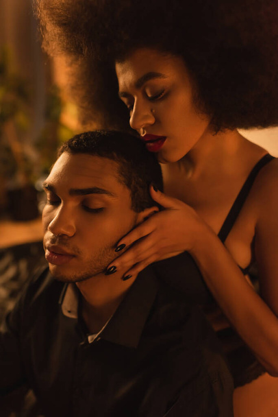 sexy african american woman with curly hair seducing young man at home - 写真・画像