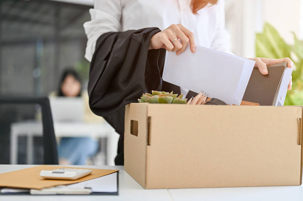 A businesswoman packing her stuff into a cardboard box at her office desk. quitting a job, career failure, unemployment, change a job. - Фото, изображение