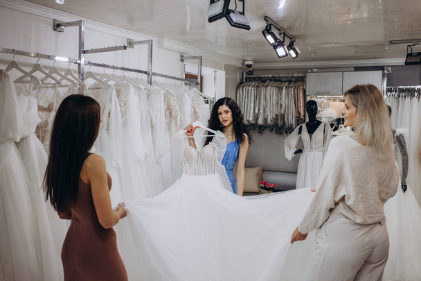 Junge Frau wählt Hochzeitskleid im Salon - Foto, Bild