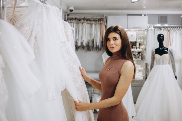 Woman choosing wedding dress in a showroom. Future bride buying a wedding gown in a shop. - Fotoğraf, Görsel