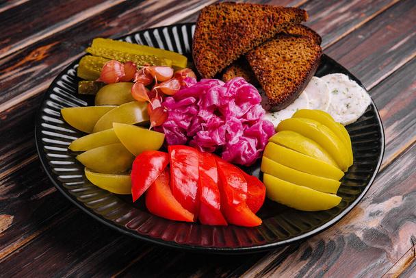 Pickles, cabbage, peppers, bread and garlic spread on a plate - Foto, afbeelding