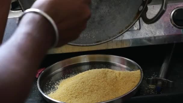 Closeup of roasted sooji or semolina poured into steel plate from steel pan to prepare dish upma - Video, Çekim