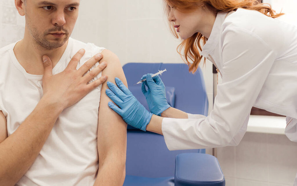 Крупним планом руки медсестри вакцинують пацієнтів шприцом. Лікар вакцинує чоловіка в лікарні. Їх лікують стерильною ін'єкційною передпліччям. ін'єкції
 - Фото, зображення