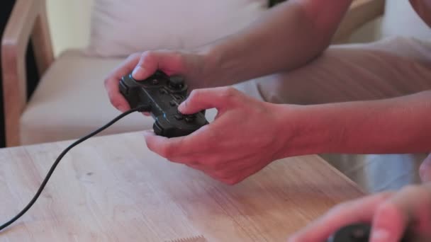 Two unrecognizable boys pressing buttons on their controllers while playing video games at home - Кадры, видео