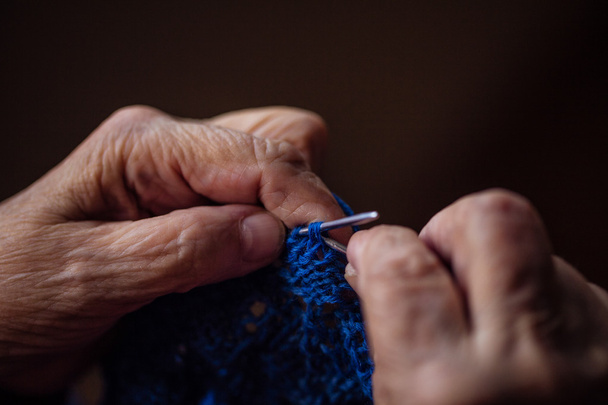 The old woman sits at home and knits garments. - Foto, imagen