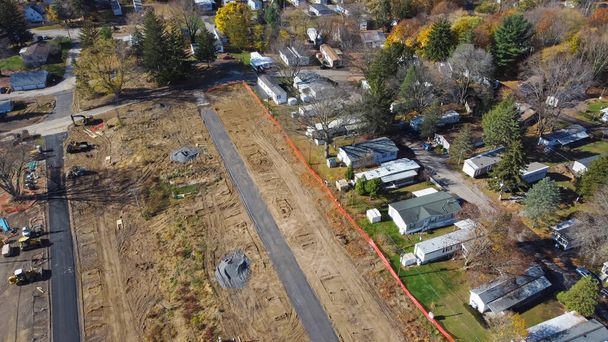 Aerial view construction site of mobile trailer park near complete manufactured houses colorful fall foliage in Rochester, New York. Infrastructure onsite of concrete slab on grade foundation support - Foto, Imagen