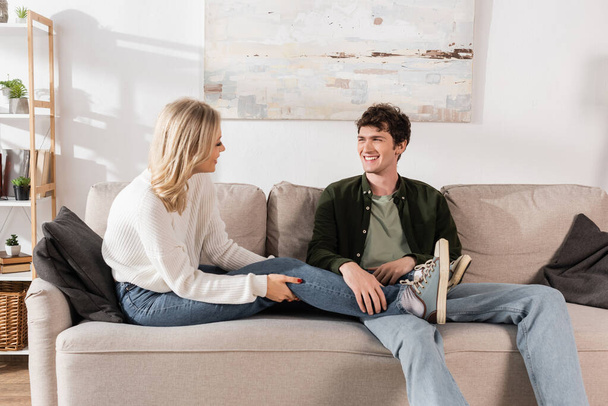 full length of cheerful couple in jeans looking at each other in living room  - Foto, immagini