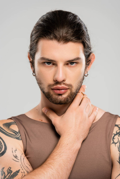 Portrait of tattooed bearded man touching face isolated on grey  - Fotografie, Obrázek