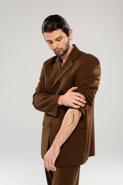 Bearded and tattooed man posing in jacket isolated on grey  - Fotografie, Obrázek