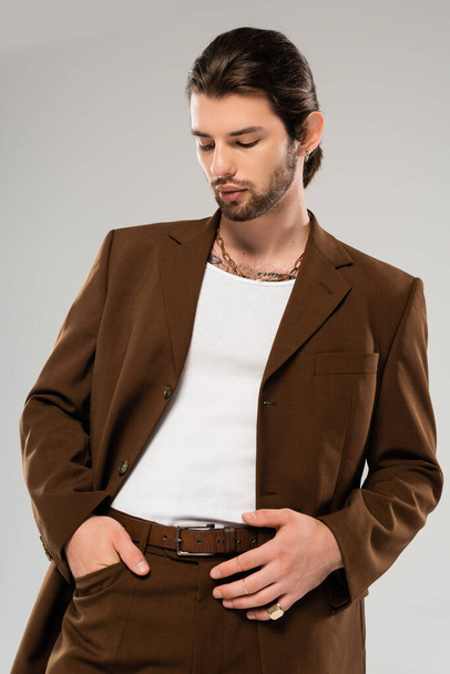 Стильний чоловік в коричневому костюмі позує ізольовано на сірому
  - Фото, зображення