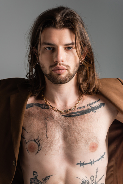 Tattooed and long haired man in jacket standing isolated on grey  - Valokuva, kuva