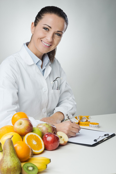 Smiling nutritionist writing medical records - Valokuva, kuva