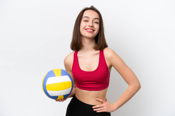 Young Ukrainian woman playing volleyball isolated on white background posing with arms at hip and smiling - Фото, зображення