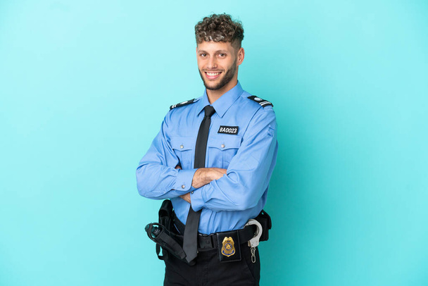 Young police blonde man isolated white on blue background with arms crossed and looking forward - Photo, Image