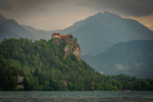 Castle near lake in Bled town in Slovenia in cloudy summer rainy day - Fotoğraf, Görsel