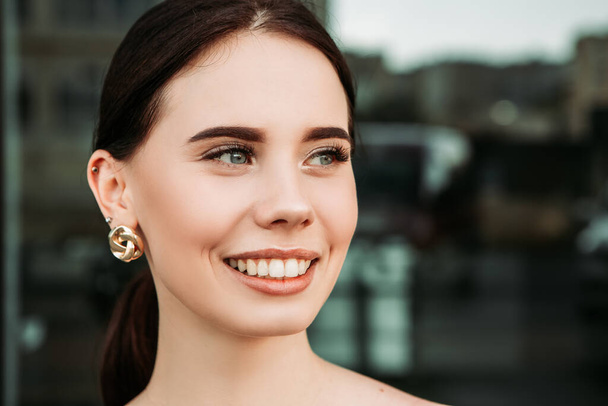 Pretty brunette caucasian woman standing outside street with white teeth beaming healthy smiling lady. Happy millennial girl model posing looking at the camera, head shot portrait. - Fotografie, Obrázek