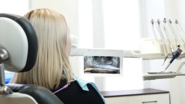 Задоволена усміхнена жінка-пацієнтка в стоматологічному кріслі. Рентгенівський знімок зуба. Рентгенографія ротової порожнини
. - Кадри, відео