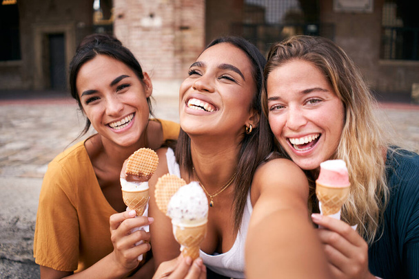 Tre giovani donne hipster sorridenti in abiti estivi. Ragazze scattare selfie foto di autoritratto su smartphone.Models posa in strada.Femmina mostrando emozioni positive viso. Foto di alta qualità - Foto, immagini