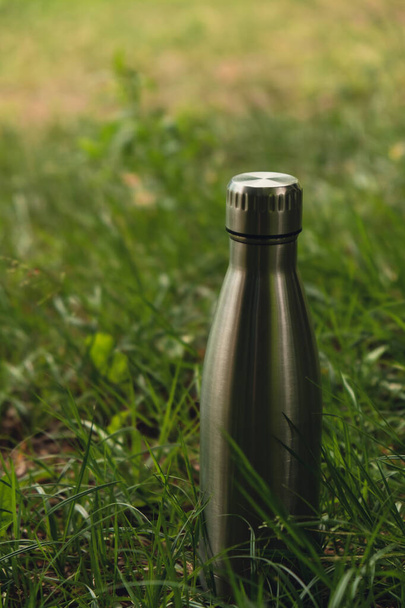 Una botella de agua. Botella de agua termo de acero reutilizable sobre hierba verde. Estilo de vida sostenible. Libre de plástico cero residuos de vida libre. Ir verde Protección del medio ambiente. Consciente de la salud. Agua termo de acero - Foto, imagen