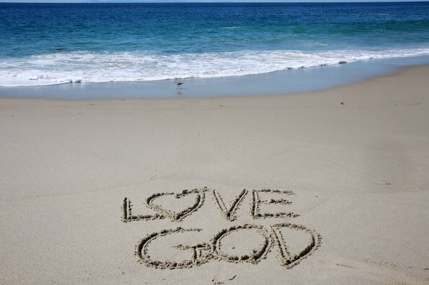 love god written in the sand on the beach.  message handwritten on a smooth sand beach - Zdjęcie, obraz
