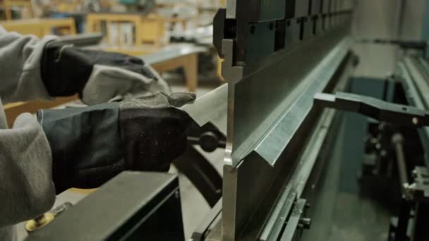 Operator bends a sheet of metal on a bending machine.Bending sheet metal. Worker cuts and bends a metal sheet on an industrial machine. CNC-controlled sheet metal bending machine in a factory. - Záběry, video
