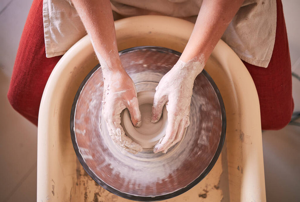 Creative, pottery and design with hands of woman in workshop studio for molding, ceramics and art. Clay, sculpture and manufacturing with girl artisan and wheel for crafting, handmade and hobby. - Fotoğraf, Görsel