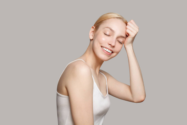 Blonde woman smiling isolated on grey background. Beauty, cosmetics, skincare - Foto, afbeelding