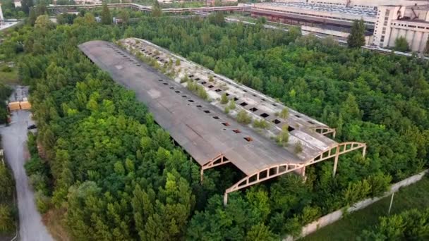 Old abandoned building. Old destroyed construction with holes in the roof and overgrown with trees around. An old ruined building with a concrete shed roof in an industrial area. Aerial drone view. - Footage, Video
