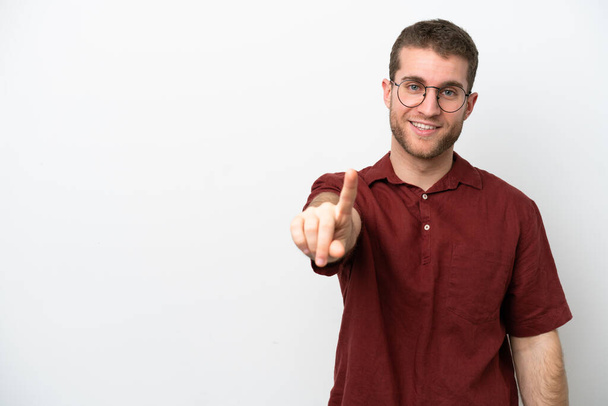 Νεαρός καυκάσιος άνδρας απομονωμένος σε λευκό φόντο που δείχνει και σηκώνει ένα δάχτυλο - Φωτογραφία, εικόνα