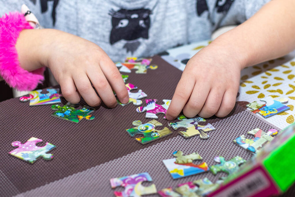 A little girl makes puzzles. Educational games for children - Foto, imagen