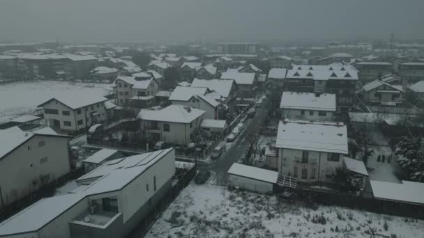 4k Aerial drone view of a city shot in landscape mode depicting homes during winter while snowing - Video