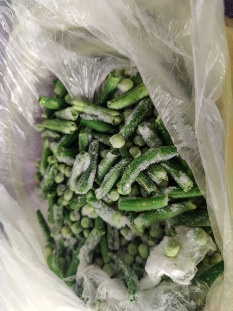 Frozen asparagus and green peas in a white plastic bag.  View from above - Foto, immagini