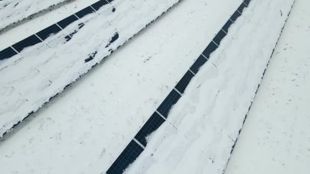 Ilmakuva lumesta kattoi kestävän sähkövoimalan, jossa oli useita rivejä aurinkosähköpaneeleita puhtaan sähköenergian tuottamiseksi. Uusiutuvista energialähteistä tuotetun sähkön heikko tehokkuus talvella. - Materiaali, video