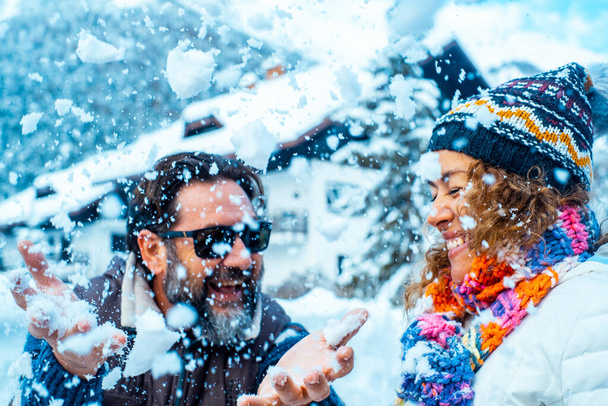 Man and woman have fun together with snow in mountains holiday vacation together. Happy couple in funny leisure activity outdoor together in winter cold season. Enjoyment and love lifestyle people - Foto, Bild