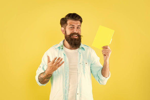 happy bearded man presenting book on yellow background, advertisement. - Foto, Bild
