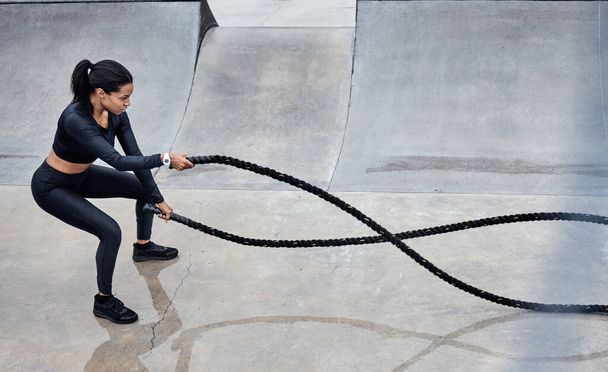 Fitness, battle ropes and strong with a black woman athlete outdoor for a workout from above. Exercise, energy and power with a female training outside using a heavy rope for cardio or endurance. - Foto, Bild